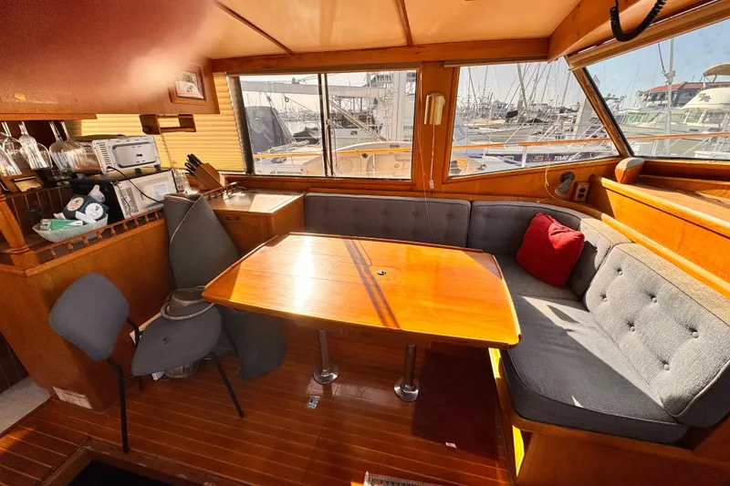 1983 Sea Ranger 45 Sun Deck interior with cozy seating and wooden table, marina view.