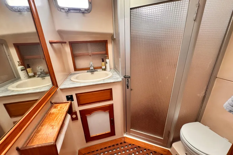 1983 Sea Ranger 45 Sun Deck bathroom with sink, shower, and wooden accents.