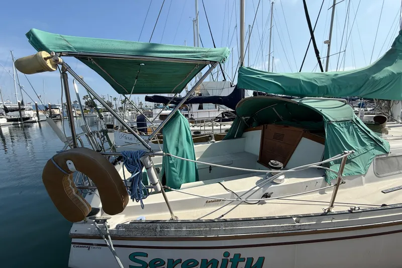 1987 Catalina 36 sailboat docked, featuring green canvas covers and a visible life preserver.