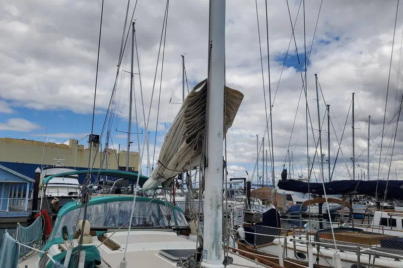 1987 Catalina 36 sailboat docked at marina under cloudy sky.