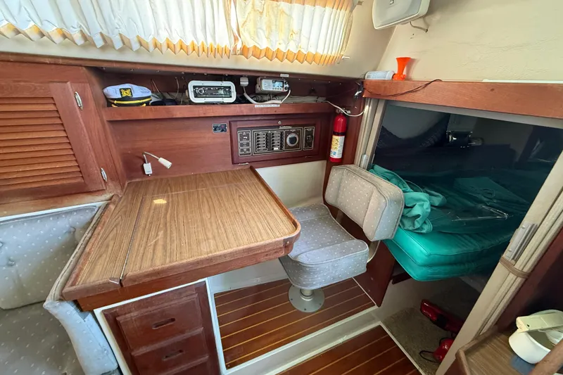 Interior of a 1987 Catalina 36 sailboat with wooden table, seating, and navigation equipment.