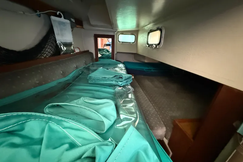 Interior cabin of a 1987 Catalina 36 sailboat with teal fabric and portholes.