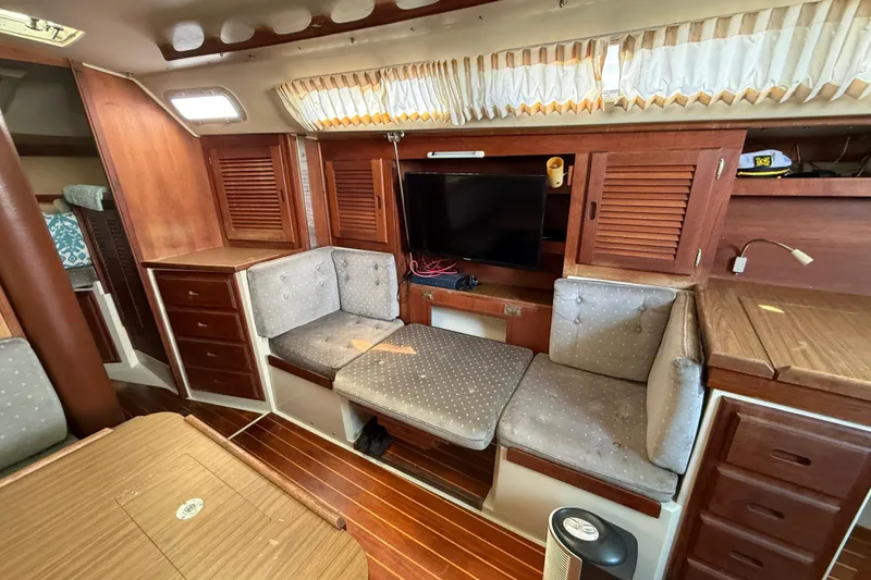 Interior of a 1987 Catalina 36 sailboat with wood paneling and cozy seating.