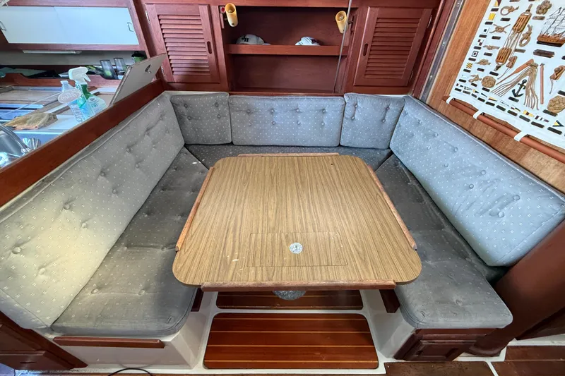 Cozy dining area in a 1987 Catalina 36 sailboat with cushioned seating and wooden table.