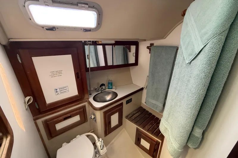 Compact bathroom in a 1987 Catalina 36 sailboat with sink, toilet, and towels.