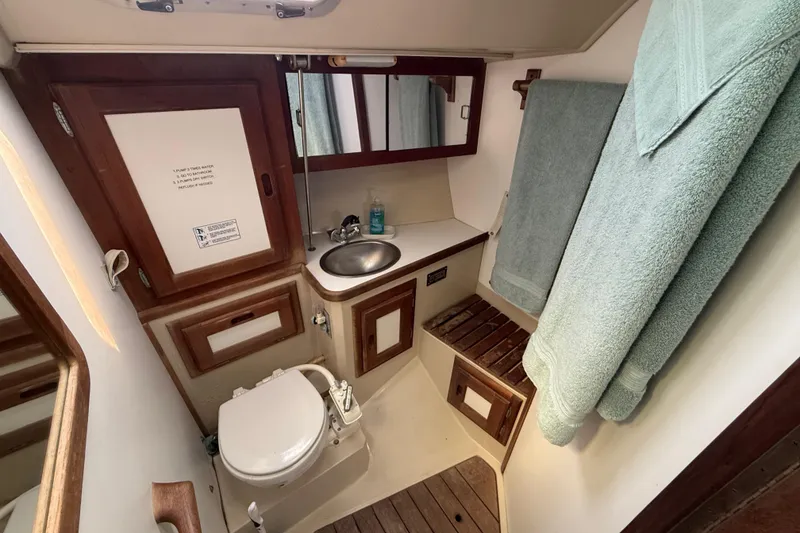 Bathroom interior of a 1987 Catalina 36 sailboat with sink, toilet, and wooden accents.