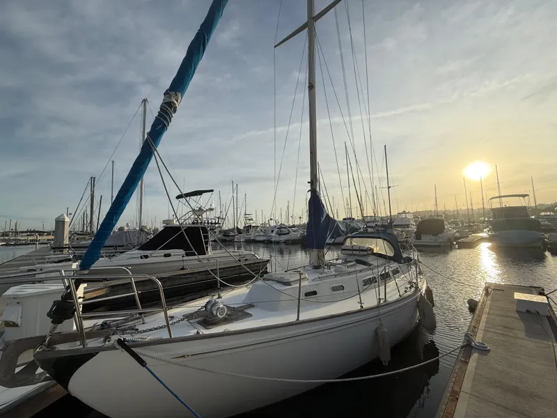 1980 Rival 32 sailboat docked at sunset in marina.