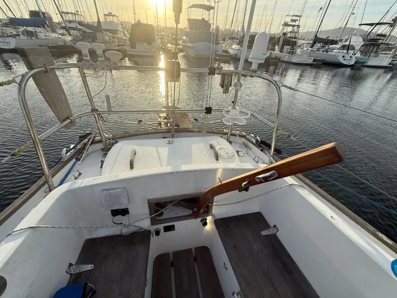 Cockpit of a 1980 Rival 32 sailboat in harbor at sunset.
