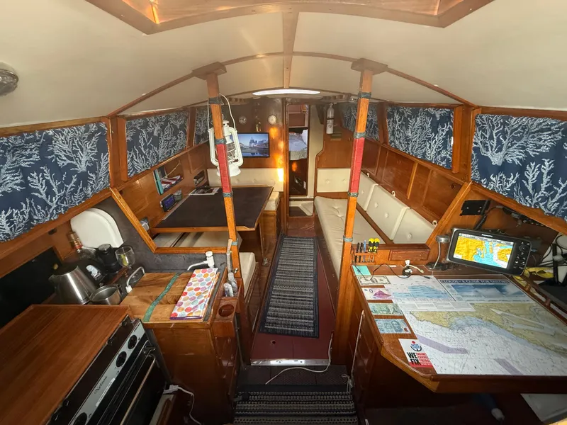 Interior of a 1980 Rival 32 yacht with maps and wooden furnishings.