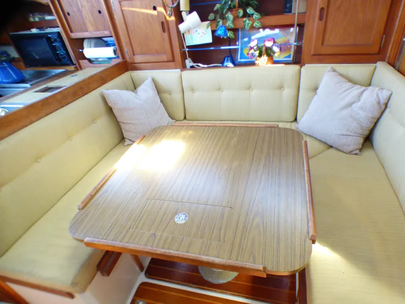 Cozy dining area in 1984 Catalina 36 Sloop with cushioned seating and wooden table.