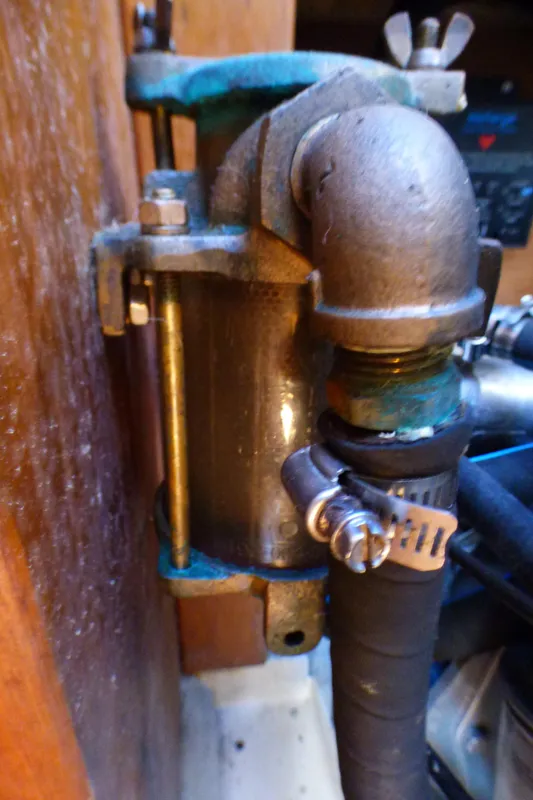 Close-up of a Catalina 36 Sloop 1984 engine component with metal fittings and hose clamp.