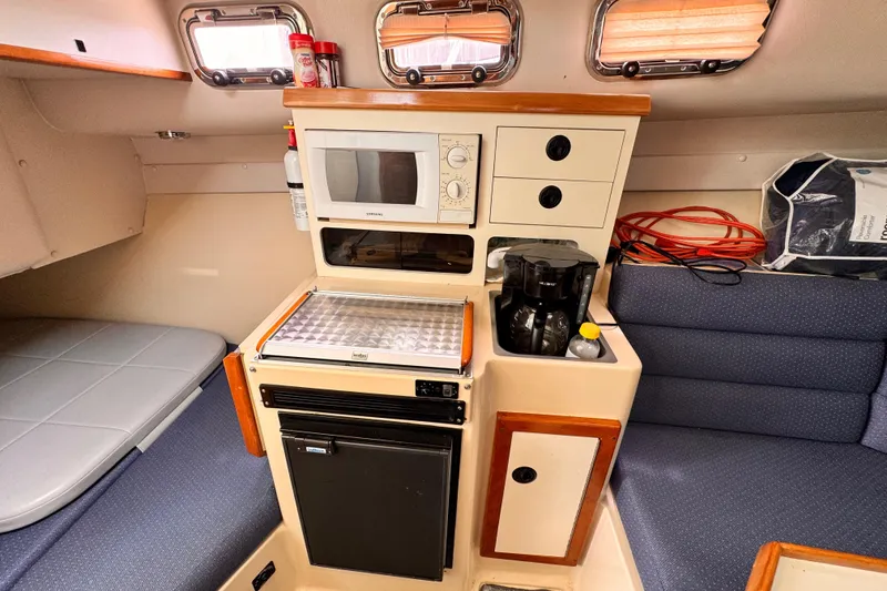 2003 Albin 28 TE cabin interior with kitchenette, microwave, and seating area.
