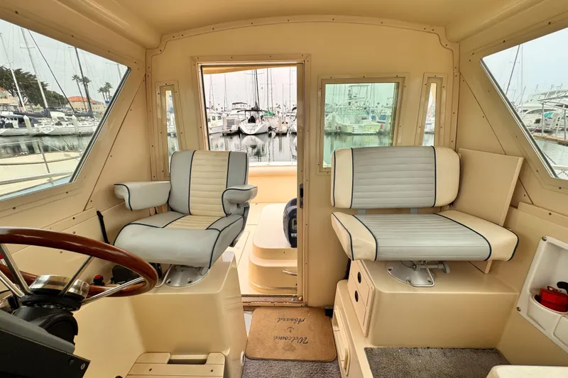 Interior of 2003 Albin 28 TE boat with two cushioned seats and marina view.