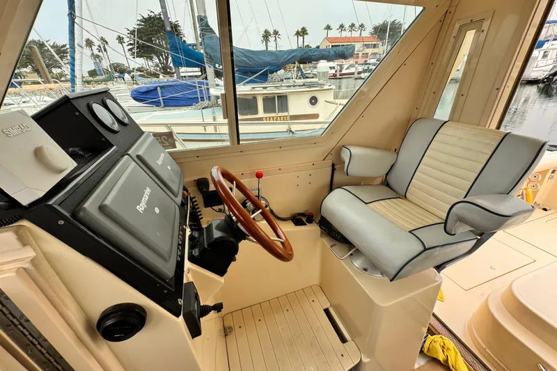 2003 Albin 28 TE boat interior with steering wheel and captain's chair in marina setting.