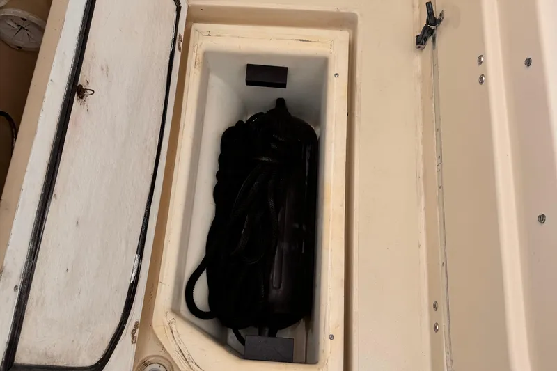 Storage compartment on a 2003 Albin 28 TE boat with coiled rope inside.