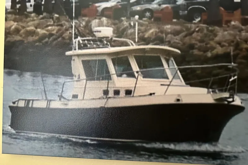 2003 Albin 28 TE boat cruising near rocky shoreline.