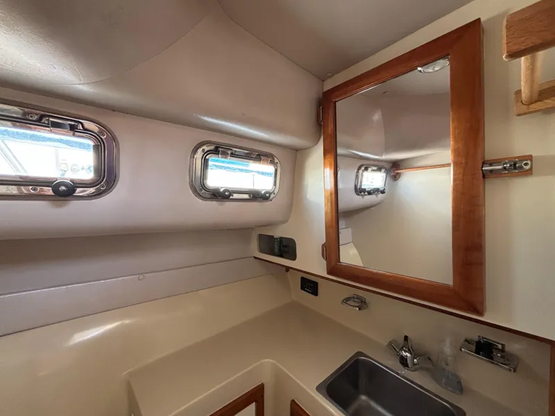 2004 Albin 28 TE boat interior with sink, mirror, and portholes.