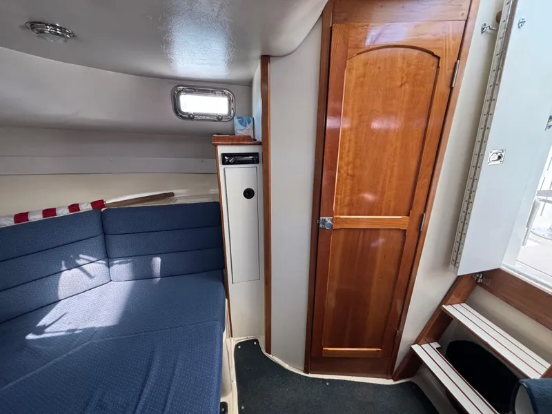 2004 Albin 28 TE cabin interior with blue seating and wooden door.