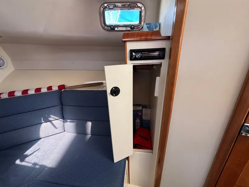 2004 Albin 28 TE cabin interior with open storage compartment and blue seating.