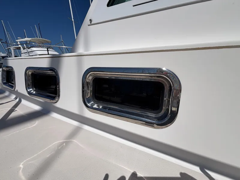 2004 Albin 28 TE boat with chrome-trimmed windows, docked under clear blue sky.