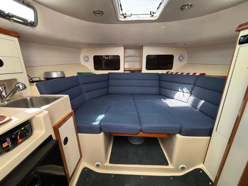Interior of 2004 Albin 28 TE boat with blue cushioned seating and compact kitchenette.