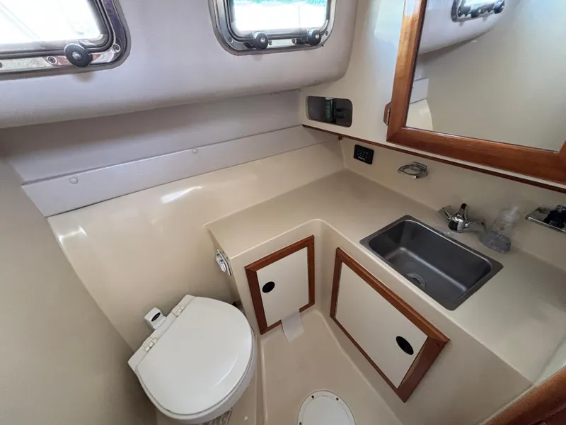 2004 Albin 28 TE boat bathroom with sink, toilet, and storage cabinets.