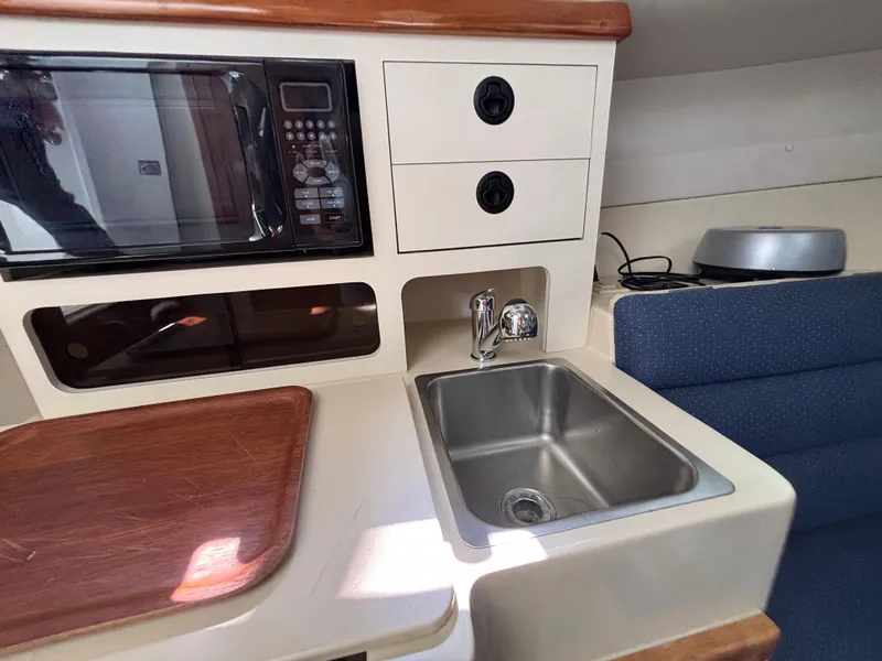Compact kitchen area in a 2004 Albin 28 TE boat with sink and microwave.