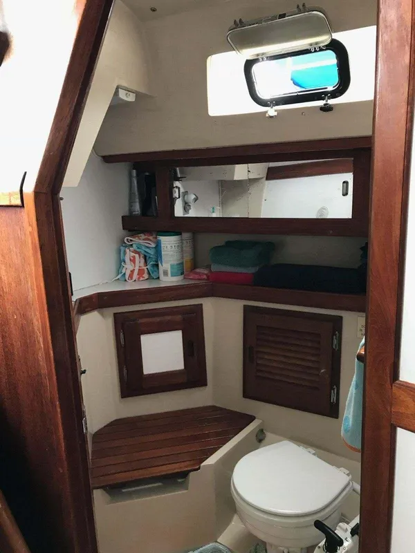 1986 Catalina 34 sailboat bathroom with wooden cabinets and a small window.