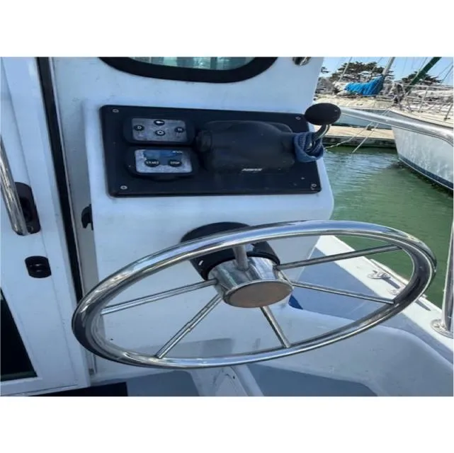 Steering wheel and controls of a 2007 Radon Signature 26 boat at a marina.