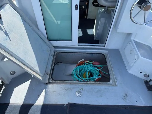 Open storage compartment on 2007 Radon Signature 26 boat with rope and equipment.