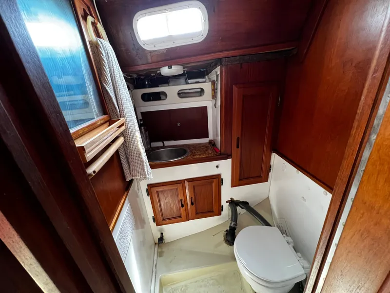 1978 Ericson 35 Sloop bathroom with wooden cabinets and a small sink.