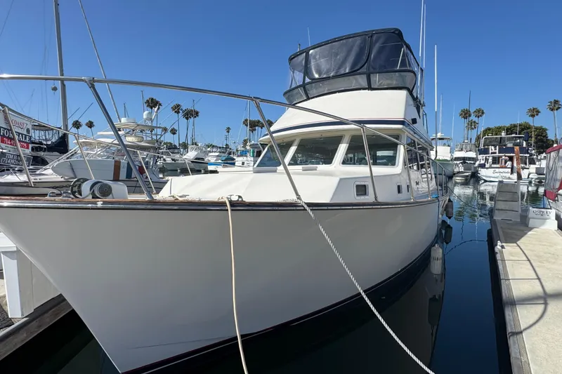1977 Tollycraft 37 Convertible yacht docked in a marina under clear blue skies.