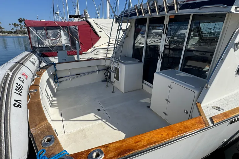1977 Tollycraft 37 Convertible boat deck with storage and ladder, docked at marina.