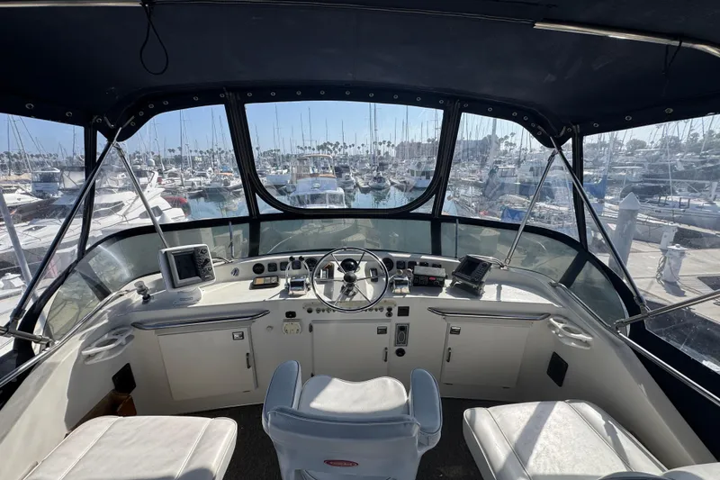 1977 Tollycraft 37 Convertible yacht helm with marina view, featuring navigation equipment and seating.