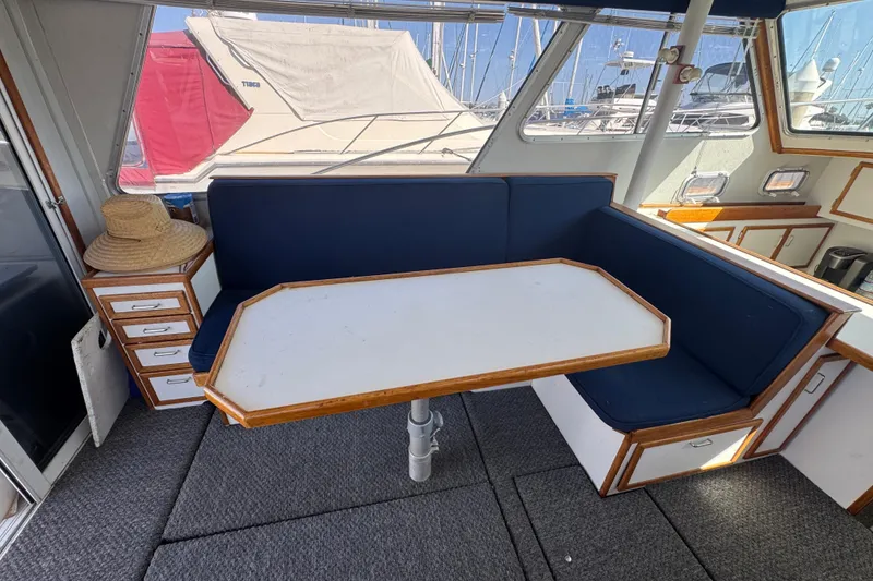 1977 Tollycraft 37 Convertible interior with blue seating and white table.