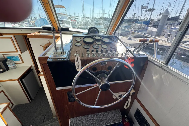 1977 Tollycraft 37 Convertible helm with steering wheel, gauges, and marina view.