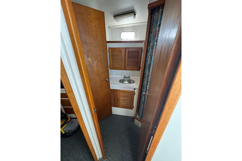 1977 Tollycraft 37 Convertible bathroom with wooden cabinets and a small sink.