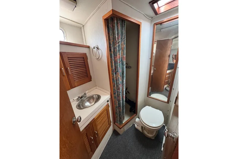 1977 Tollycraft 37 Convertible bathroom with sink, toilet, and shower curtain.