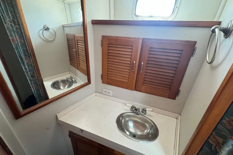 1977 Tollycraft 37 Convertible bathroom with wooden cabinets and stainless steel sink.