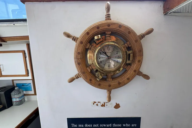Wooden ship wheel clock on Tollycraft 37 Convertible, 1977, with nautical decor.