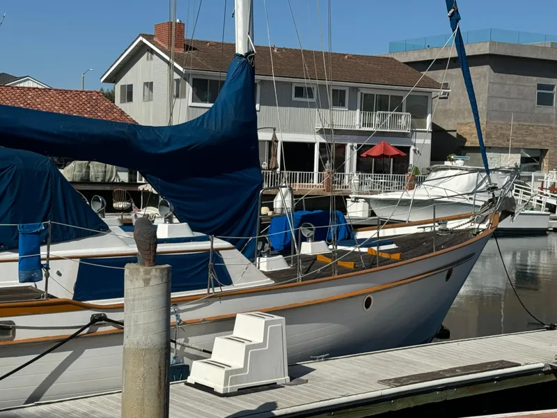 1984 Transpacific Marine Ketch docked at marina, with residential backdrop.