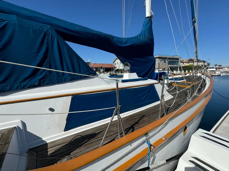1984 Transpacific Marine Ketch sailboat docked, featuring blue covers and wooden deck.