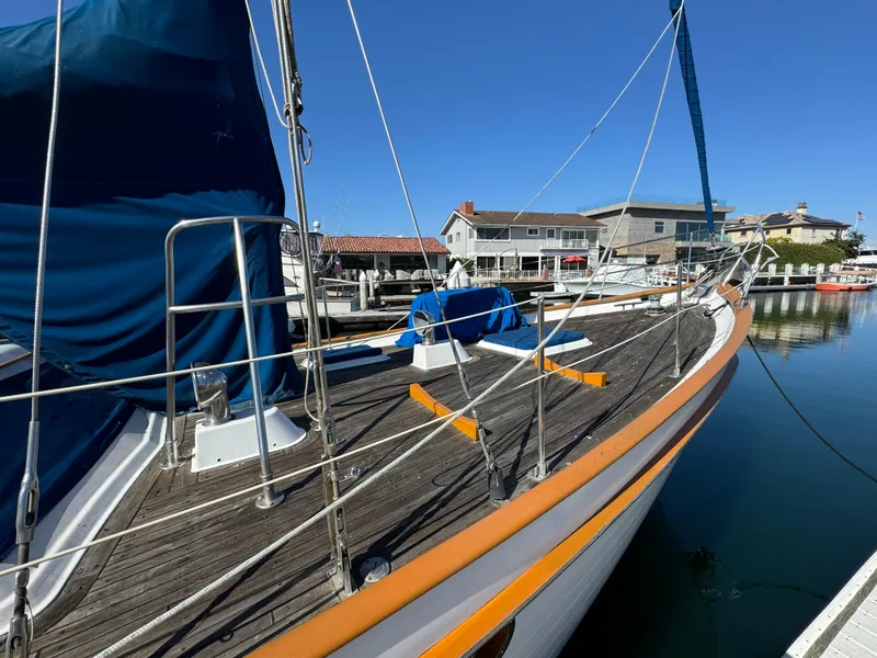 1984 Transpacific Marine Ketch docked at a marina, showcasing its wooden deck and blue sail cover.