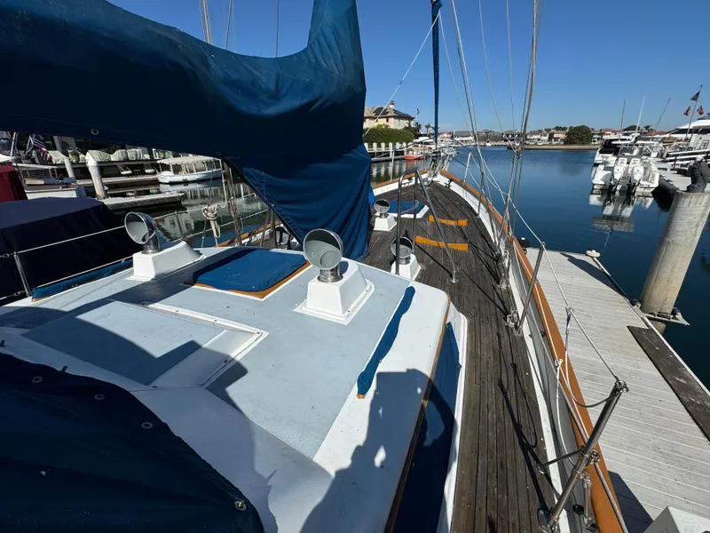 1984 Transpacific Marine Ketch docked at marina, featuring blue sails and wooden deck.