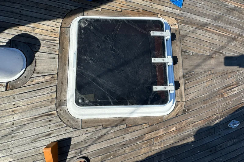 Deck hatch on 1984 Transpacific Marine Ketch with wooden planks and metal hinges.