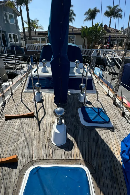 1984 Transpacific Marine Ketch deck with winches and blue covers, docked near palm trees.