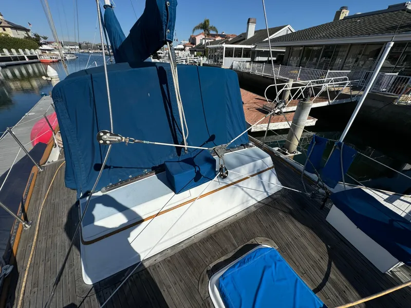 1984 Transpacific Marine Ketch with blue covers docked at a marina.