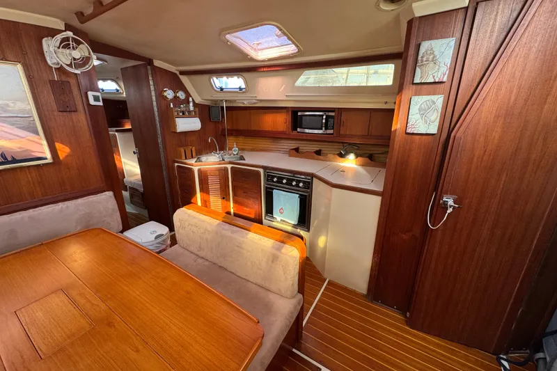 Interior of a 1989 Catalina 42 sailboat with wood finishes and compact kitchen.