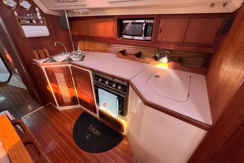 1989 Catalina 42 yacht kitchen with wood cabinetry, stove, sink, and microwave.
