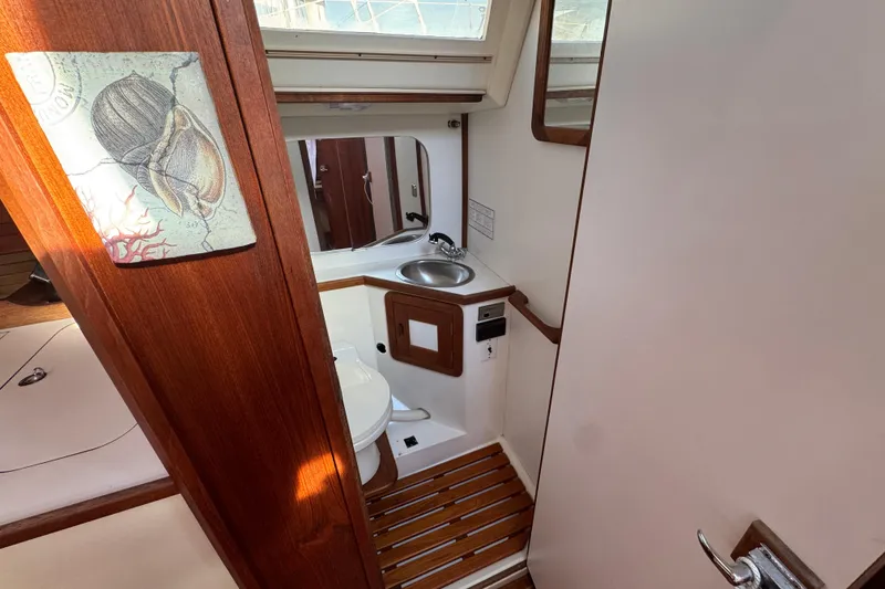 Interior of 1989 Catalina 42 sailboat bathroom with wooden accents and nautical decor.